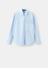 Camisa celeste de corte oversize, con mangas largas, cuello camisero, cierre frontal con botones y detalle de bordado floral en el pecho.
