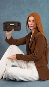 Billetera larga de diseño rectangular con estampado animal print en tonos oscuros. Cuenta con cierre perimetral, solapa frontal con broche a presión y placa metálica decorativa con logo. Su interior está organizado con múltiples tarjeteros, visores, bolsillos y un compartimento específico para billetes, además de un monedero con cierre.