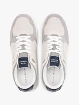 Zapatillas de corte bajo inspiradas en modelos retro de baloncesto, con exterior de ante y paneles de malla en tonos grises y beige. Presentan suela de goma blanca gruesa, cierre de cordones y detalles distintivos de la marca Tommy Hilfiger en el lateral, lengüeta y talón.