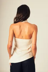 Top de lino color crudo, con cuello halter alto y diseño sin mangas.