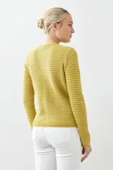 Chaqueta de punto color rojo, de corte entallado y manga larga. Presenta cuello redondo y cierre frontal con botones metálicos dorados texturizados.
