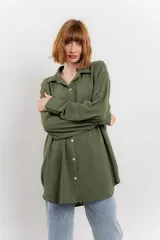 Camisa verde militar con estampado de lunares blancos, de corte oversize, con cuello camisero, cierre frontal con botones y bolsillo en el pecho.