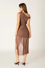 Vestido midi de color marrón mocha, con diseño de un solo hombro y detalle de fruncido en la cintura. La falda presenta un corte asimétrico con una abertura lateral que aporta movimiento y fluidez a la prenda.