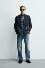 Blazer de corte regular confeccionada en lana, con diseño de botonadura cruzada y solapas de pico. Presenta mangas largas, bolsillos de vivo en el pecho y la cadera, un bolsillo interior y una abertura central en la espalda.
