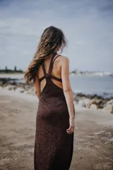 Vestido largo de viscosa con lurex color marrón con espalda descubierta y tiras cruzadas. Diseño de dos piezas con cuello choker.