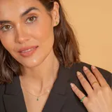 Anillo de oro amarillo 18k con diseño de media alianza engastado con esmeraldas en talla cuadrada.