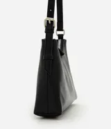 Cartera tipo baguette de tamaño pequeño, confeccionada en poliuretano con acabado brillante. Presenta un diseño minimalista con cierre de cremallera metálica superior, herrajes en níquel y correa de hombro ajustable con hebilla.