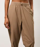 Pantalón jogger deportivo de microfibra, color tostado, con cintura elástica ajustable y puños elásticos en los tobillos. Diseño funcional y liviano, ideal para actividades físicas.
