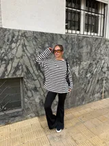 Conjunto compuesto por remera de manga larga oversize a rayas horizontales blancas y negras con escote bote, y pantalón negro de corte flared.