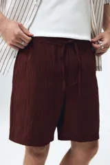Short de corte relaxed fit confeccionado en suave tejido texturizado de mezcla de viscosa, en color bordó. Cuenta con cintura elástica con cordón ajustable, bolsillos laterales discretos y un bolsillo trasero ojal.