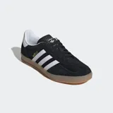 Championes Adidas Gazelle Indoor negros de gamuza con las tres tiras blancas y suela de goma color caramelo.