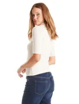 Remera de tejido rib marca Elie Tahari, color beige, con cuello mock y mangas cortas. Presenta un pequeño avío metálico con logo en el ruedo.