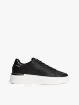 Zapatillas de plataforma Tommy Hilfiger, color negro con suela blanca. Presentan un diseño de corte bajo con cordones, confeccionadas en cuero y material sintético, con el monograma TH en el lateral y detalles metálicos en el talón.