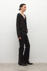 Jean negro de tiro medio, corte bootcut, con tachas metálicas plateadas decorando los laterales de las piernas y el ruedo.