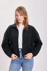 Campera de polar negro con cierre frontal, cuello alto, bolsillos laterales y corte holgado.