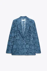 Blazer azul de encaje floral, con cuello solapa, manga larga con hombreras, falsos bolsillos delanteros y cierre frontal con un botón.