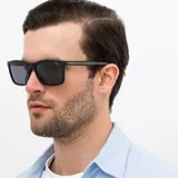 Lentes de sol INVU con montura cuadrada negra y lentes polarizadas grises. Patillas color verde oliva.