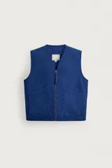 Chaleco de algodón azul, de corte relaxed fit, ligeramente acolchado con pespuntes, cuello en pico, cierre frontal con cremallera y bolsillos de plastrón en la cadera.