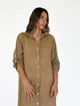 Vestido camisero largo de lino, color mostaza, con cuello camisero, cierre frontal de botones y mangas tres cuartos con detalle de tejido calado en los laterales.