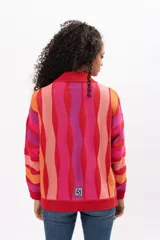 Buzo de tejido de punto con diseño de rayas verticales onduladas en tonos vibrantes como rojo, fucsia, naranja y rosa. Presenta cuello redondo, puños y ruedo acanalados, con un corte holgado y cómodo.