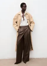 Pantalón wide leg de efecto piel color marrón, con tiro medio, bolsillos laterales, pinzas delanteras y cierre frontal con botón, gancho y cremallera ocultos. Cuenta con forro interior.