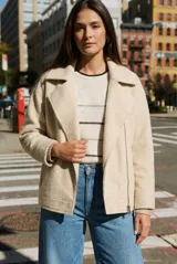 Campera de textura suave en color beige, con diseño tipo biker, cierre frontal cruzado y bolsillos laterales con cierre.