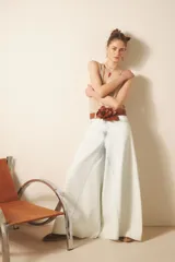 Jean de tiro alto y corte ultra ancho, confeccionado en denim rígido con lavado bleach que le otorga un tono casi blanco. Presenta recortes estratégicos en las piernas y el tiro, brindando una silueta con gran vuelo y movimiento. Incluye cierre y botón frontal, además de forrería interna estampada.