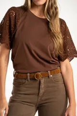 Remera de algodón peinado color negro, con mangas cortas de broderie con diseño calado y terminación festoneada. Presenta un corte oversize y cuello redondo.