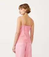 Blusa musculosa de color rosado confeccionada en tejido laise de algodón. Presenta un escote en V con un lazo decorativo en el frente, tirantes finos y detalle de lastex en la espalda para un mejor ajuste.
