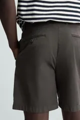 Bermuda de hombre color beige claro, corte regular fit, con pliegues frontales, bolsillos delanteros y bolsillos traseros de doble vivo con botón.