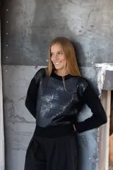 Buzo negro de manga larga con panel frontal decorado con parches de lentejuelas cuadradas. Presenta cuello redondo y puños y ruedo en tejido acanalado.