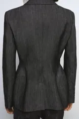 Blazer de mujer color gris oscuro, con efecto denim o tejido texturizado. Presenta cuello solapa de muescas, hombreras, bolsillos con solapa en el delantero y cierre frontal de dos botones oscuros.