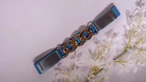 Cinto elastizado color verde con aplique de cadena dorada.