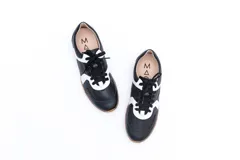 Zapatillas Magnolia de cuero negro con detalles en blanco y suela marrón.