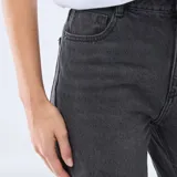 Jean de corte recto y tiro medio, confeccionado en denim de algodón color negro. Presenta diseño clásico de cinco bolsillos, cierre frontal con cremallera y botón metálico.