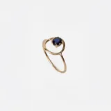 Anillo de oro 18k con diseño minimalista que presenta un zafiro azul engastado en un círculo metálico.