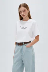 Remera de manga corta negra, con cuello redondo y estampado de texto blanco en el pecho.
