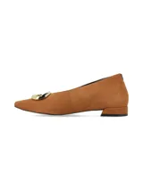 Zapato plano de nobuck color camel, con punta fina, tacón bajo cuadrado y detalle de aplique metálico dorado en la parte frontal.