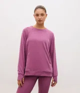 Buzo cerrado deportivo de corte oversized, color violeta, con cuello redondo, mangas largas con puños acanalados y bolsillo frontal funcional. Presenta detalles de encaje en los laterales y ruedo acanalado.