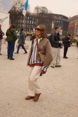 Buzo tejido de punto con diseño a rayas verticales en color celeste y marrón chocolate. Presenta un cuello polo con solapa en color crema y cierre frontal de tres botones, mangas largas de corte holgado y terminaciones en tejido acanalado.