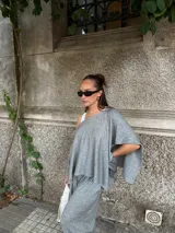 Blusa de lanilla gris con diseño asimétrico de un solo hombro y corte holgado tipo capa.