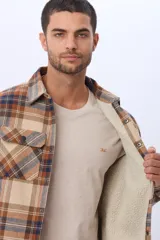 Campera tipo camisa de viyela a cuadros, con interior forrado en corderito, cierre frontal con botones y dos bolsillos frontales con solapa.