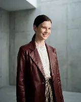 Blazer de cuero bovino color bordó, con silueta entallada, solapas clásicas y cierre frontal con un botón. Presenta mangas largas con detalles fruncidos que aportan textura.