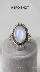 Anillo de plata 925 con piedra central ovalada de nácar y borde decorativo con textura estriada.