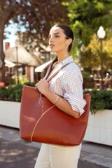 Bolso tote de cuero color marrón con costuras blancas a contraste. Tiene doble asa de hombro y diseño minimalista.
