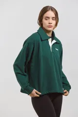 Buzo de algodón en color verde inglés, con diseño de cuello tipo chomba con botones frontales y detalles en blanco. Presenta un corte holgado y cómodo con mangas largas.