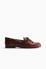 Zapatos náuticos de cuero marrón con cordones en el empeine, ojetes metálicos y costura tipo mocasín en la puntera.