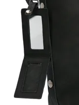 Cartera tipo tote de la marca Hush Puppies, color negro, con diseño minimalista y cierre superior. Incluye un colgante decorativo con el logo de la marca y correas ajustables.