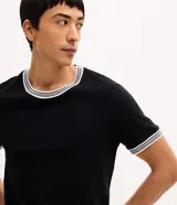 Remera regular de manga corta y cuello redondo color negro, con diseño texturizado y detalles de rayas contrastantes en cuello y puños.