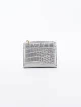 Billetera pequeña color plateado con textura de cocodrilo y cierre superior con cremallera dorada.